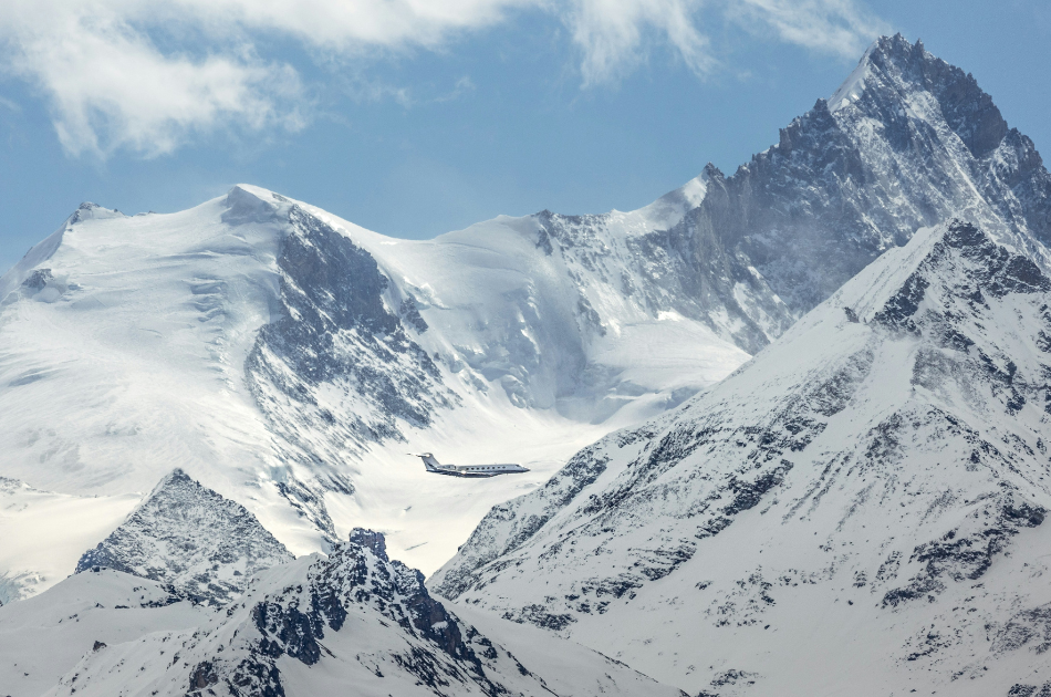 Private jet flying by snowy mountains for a winter escape
